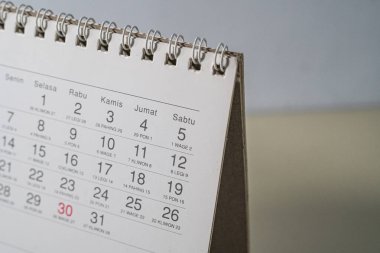 Belirli bir tarihi gösteren beyaz masa takviminin açılı bir makro perspektiften çekilmiş halini kapat. Üretkenlik blogları, planlamacılar ve web siteleri içeriği için harika