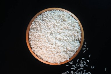 Siyah zemin üzerine kurulmuş tahta bir kasede beyaz pirinç. Gıda ambalajı, minimalist mutfak görselleri, restoran menüleri veya malzeme odaklı ürün tasarımı için mükemmel.