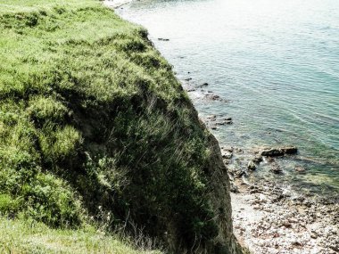 Karadeniz kıyısındaki kayalıklarda yeşil çimenler. Romanya 'nın Dobrogea bölgesinin Vama Veche kentindeki kayalıkların manzarası ve plajlar. Doğa ve seyahat kavramı.