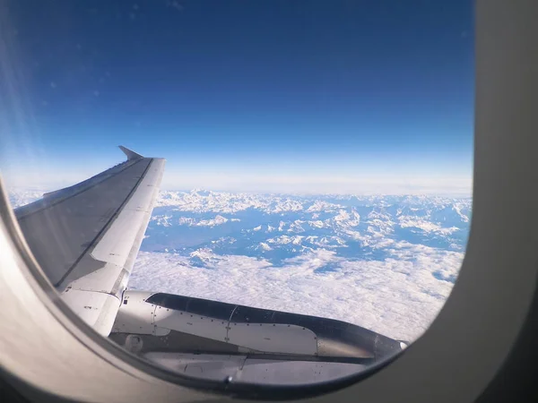 Beautiful view of aircraft wing and Alps from the plane window. Travel concept.