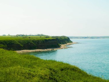 Karadeniz kıyısındaki kayalıklarda yeşil çimenler. Romanya 'nın Dobrogea bölgesinin Vama Veche kentindeki kayalıkların manzarası ve plajlar. Doğa ve seyahat kavramı.