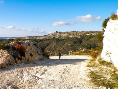 Yaz mevsiminde bir turist dağ yolunda yürüyor. Kıbrıs adasındaki Troodos Dağları. Paphos bölgesine yakın. Boşluğu mavi gökyüzünde kopyala.