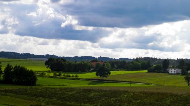 Rainy day over green hills and meadows of Kashubian Region, Poland. Copy space on cloudy sky.