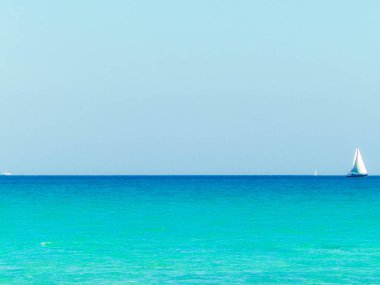 A boat in the turquoise waters of the Mediterranean Sea. Copy space on blue sky. Travel and leisure concept.