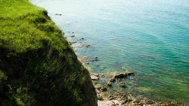 Karadeniz kıyısındaki kayalıklarda yeşil çimenler. Romanya 'nın Dobrogea bölgesinin Vama Veche kentindeki kayalıkların manzarası ve plajlar. Doğa ve seyahat kavramı.