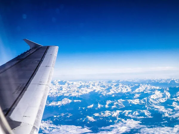 Beautiful view of aircraft wing and Alps from the plane window. Travel concept.