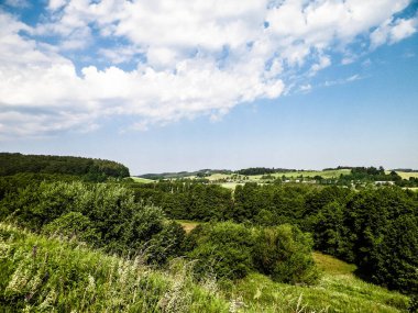 Tepeler, tarlalar ve çayırlar. Wiezyca 'nın güzel manzarası, Kashubia Bölgesi, Kuzey Polonya. Boşluğu mavi gökyüzünde kopyala.