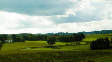 Rainy day over green hills and meadows of Kashubian Region, Poland. Copy space on cloudy sky.