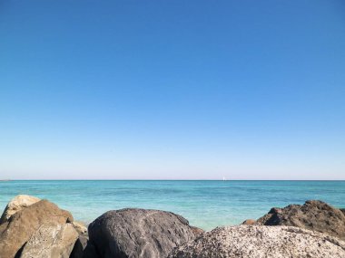 Vada sahilindeki taşlar, şeffaf, turkuaz su ve beyaz kum. Seyahat ve doğa kavramı.