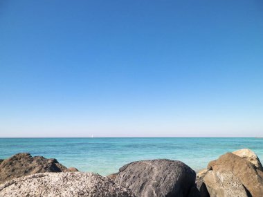 Vada sahilindeki taşlar, şeffaf, turkuaz su ve beyaz kum. Seyahat ve doğa kavramı.