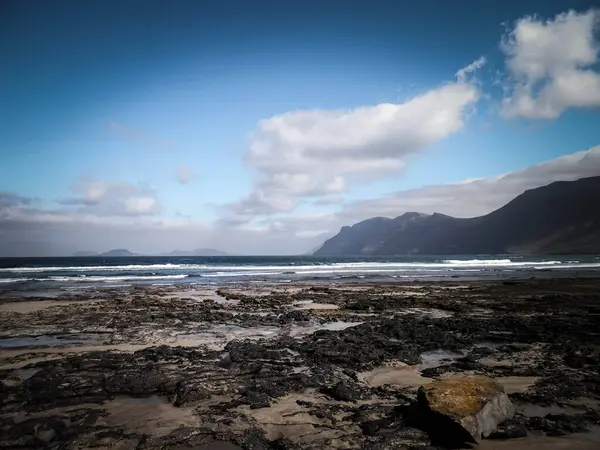 Caleta de Famara 'da güzel bir sahil, Lanzarote Kanarya Adaları. Caleta de Famara 'daki plaj sörfçüler arasında çok popüler..