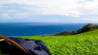 Rucksack on cliff, and sea in a background. Travel concept. Sao Miguel island, Azores.