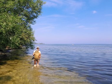 Oslonino yakınlarındaki Pucka Körfezi 'nin kıyı bölgesinin keşfi. Baltık deniz suyunda yürüyen bir turist.