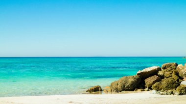 Vada sahilindeki taşlar, şeffaf, turkuaz su ve beyaz kum. Seyahat ve doğa kavramı.