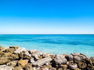 Vada sahilindeki taşlar, şeffaf, turkuaz su ve beyaz kum. Seyahat ve doğa kavramı.