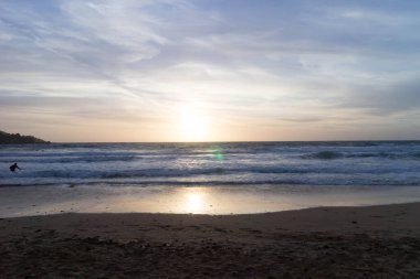 Melieha sahilinde sörfçü olarak. Golden Bay Malta 'da günbatımı. Doğa kavramının spor ve güzelliği.