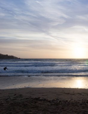 Melieha sahilinde sörfçü olarak. Golden Bay Malta 'da günbatımı. Doğa kavramının spor ve güzelliği.