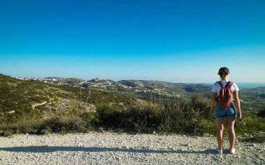 Yaz mevsiminde bir turist dağ yolunda yürüyor. Kıbrıs adasındaki Troodos Dağları. Paphos bölgesine yakın. Boşluğu mavi gökyüzünde kopyala.