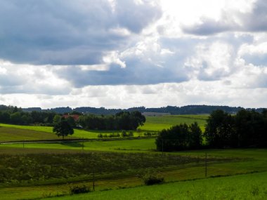 Rainy day over green hills and meadows of Kashubian Region, Poland. Copy space on cloudy sky.