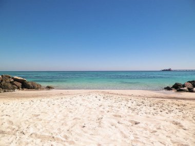 Vada sahilindeki taşlar, şeffaf, turkuaz su ve beyaz kum. Seyahat ve doğa kavramı.