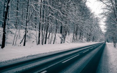 Road across forest in Wiezyca. Winter season in northern Poland. Transport and nature concept.
