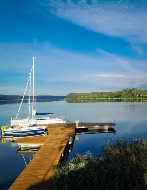 Sailing on Lake Wdzydze. A sailboat moored at the shore of the lake. Wdzydze is one of the largest Polish lakes. It is located in the Tucholskie Forests in Northern Poland. clipart