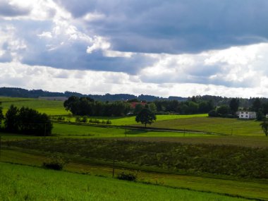 Rainy day over green hills and meadows of Kashubian Region, Poland. Copy space on cloudy sky.