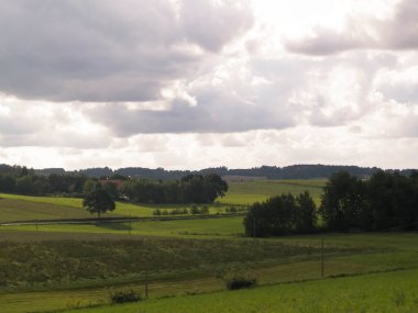 Rainy day over green hills and meadows of Kashubian Region, Poland. Copy space on cloudy sky.