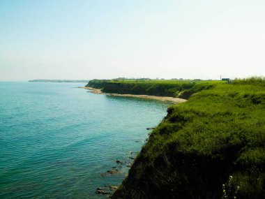 Karadeniz kıyısındaki kayalıklarda yeşil çimenler. Romanya 'nın Dobrogea bölgesinin Vama Veche kentindeki kayalıkların manzarası ve plajlar. Doğa ve seyahat kavramı.