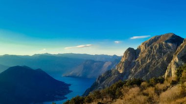 Lovcen dağı güneşli bir günde zirveye çıkar. Karadağ 'daki Boka Kotorska çevresinde Lovcen Dağları bulunuyor. Kotorska körfezi önplanda.