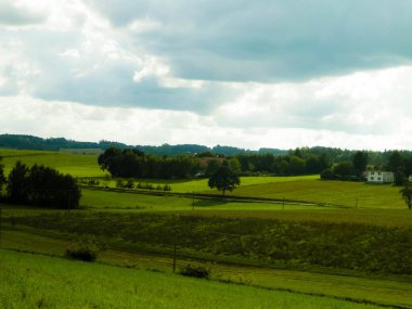 Rainy day over green hills and meadows of Kashubian Region, Poland. Copy space on cloudy sky.