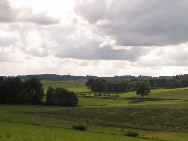 Rainy day over green hills and meadows of Kashubian Region, Poland. Copy space on cloudy sky.