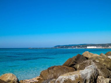 Stones on the beach in Vada, transparent, turquoise water and white sand. Travel and nature concept. clipart