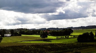 Rainy day over green hills and meadows of Kashubian Region, Poland. Copy space on cloudy sky.