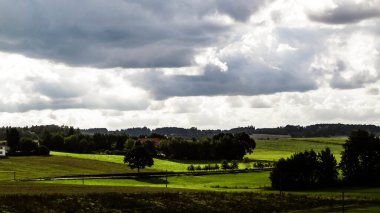 Rainy day over green hills and meadows of Kashubian Region, Poland. Copy space on cloudy sky.