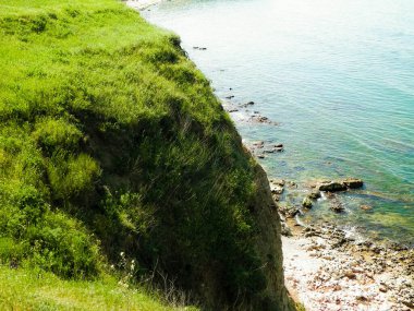 Karadeniz kıyısındaki kayalıklarda yeşil çimenler. Romanya 'nın Dobrogea bölgesinin Vama Veche kentindeki kayalıkların manzarası ve plajlar. Doğa ve seyahat kavramı.