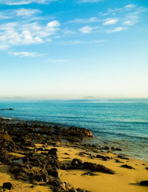 Playa Blanca 'da Kanarya kıyıları, plajlar, kayalar ve Atlantik Okyanusu. Lanzarote adasının tipik kıyıları. Tatil ve turizm konsepti.