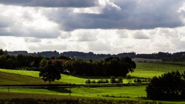 Rainy day over green hills and meadows of Kashubian Region, Poland. Copy space on cloudy sky.