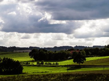 Rainy day over green hills and meadows of Kashubian Region, Poland. Copy space on cloudy sky.