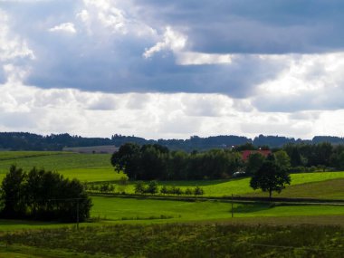 Rainy day over green hills and meadows of Kashubian Region, Poland. Copy space on cloudy sky.