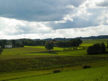 Rainy day over green hills and meadows of Kashubian Region, Poland. Copy space on cloudy sky.