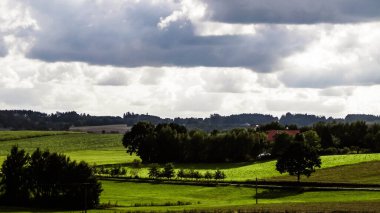 Rainy day over green hills and meadows of Kashubian Region, Poland. Copy space on cloudy sky.