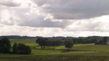 Rainy day over green hills and meadows of Kashubian Region, Poland. Copy space on cloudy sky.