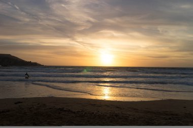 Melieha sahilinde sörfçü olarak. Golden Bay Malta 'da günbatımı. Doğa kavramının spor ve güzelliği.