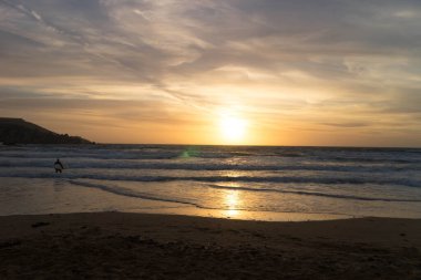 Melieha sahilinde sörfçü olarak. Golden Bay Malta 'da günbatımı. Doğa kavramının spor ve güzelliği.