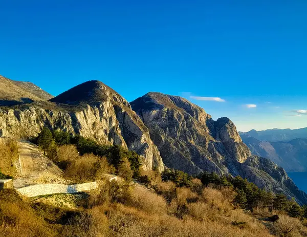 Lovocen Dağı tepeleri ve Kotor Körfezi fiyortları üzerinde güneşli bir gün. Karadağ 'daki Boka Kotorska çevresinde Lovcen Dağları bulunuyor. Kotorska körfezi önplanda.