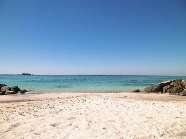 Vada sahilindeki taşlar, şeffaf, turkuaz su ve beyaz kum. Seyahat ve doğa kavramı.