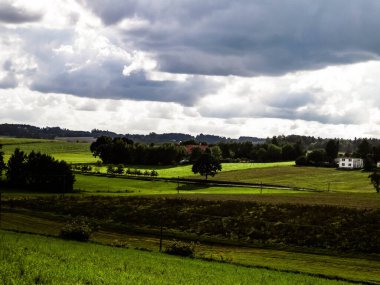 Rainy day over green hills and meadows of Kashubian Region, Poland. Copy space on cloudy sky.