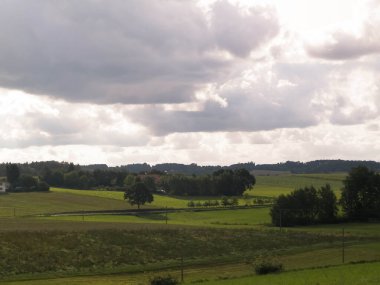 Rainy day over green hills and meadows of Kashubian Region, Poland. Copy space on cloudy sky.