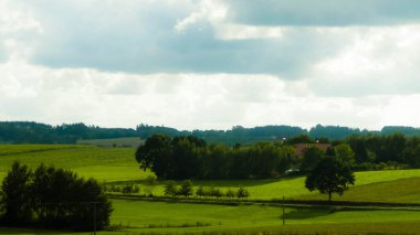 Rainy day over green hills and meadows of Kashubian Region, Poland. Copy space on cloudy sky.